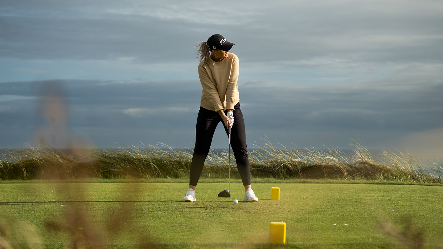 Olivia tees off with the Irish Sea at her back.